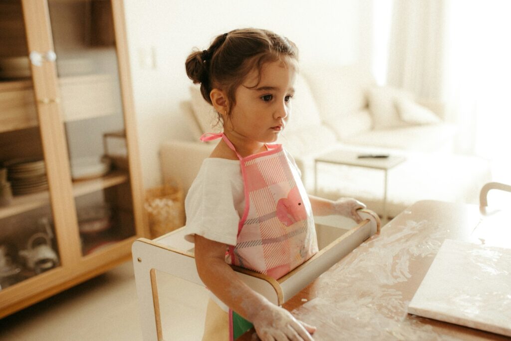 A child dusting flour while baking